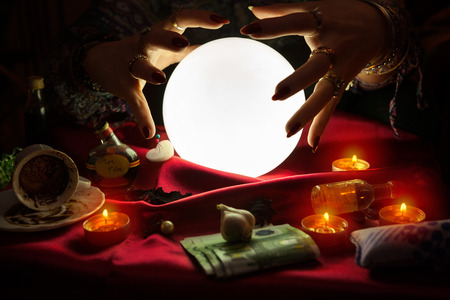 Hands from fortune teller above illuminated crystal ballの写真素材