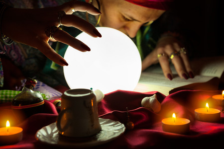 Old gypsy fortune teller woman looking and reading the spells from the bookの写真素材