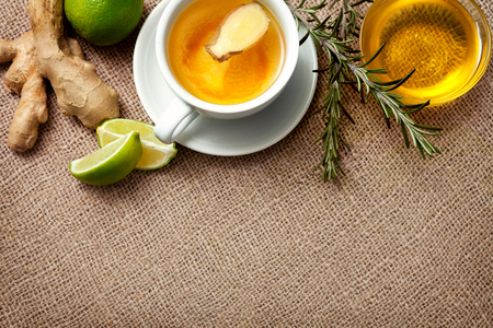 Cup of ginger tea with honey, ginger and lime on the tableの写真素材