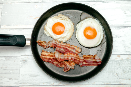 Top view of fried egg in a pan with bacon, freshly made breakfast with egg and baconの写真素材