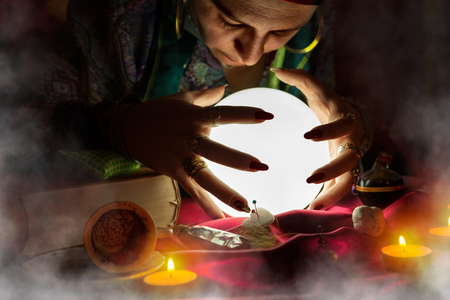 Gypsy woman fortune teller looking at shining crystal ballの写真素材