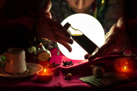 Gypsy woman fortune teller holding and showing bottle with potionの写真素材