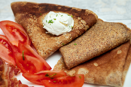 Breakfast pancakes with sour cream,bacon and tomatoesの写真素材