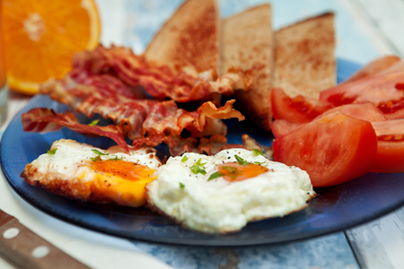Fried eggs,tomatoes and crispy bacon-breakfast on plateの写真素材