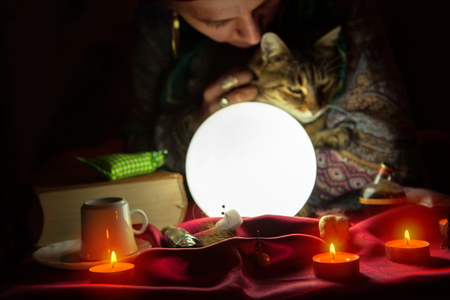 Woman fortuneteller during session with crystal ball and catの写真素材