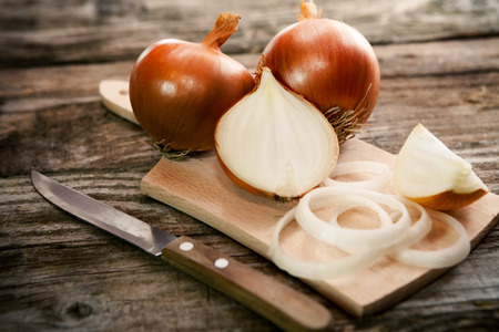 Cut fresh bulb of onion on cutting board and knifeの写真素材