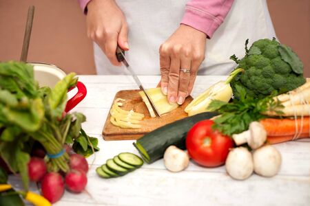 Woman slicing yellow pepper with a knife on cutting boardの写真素材