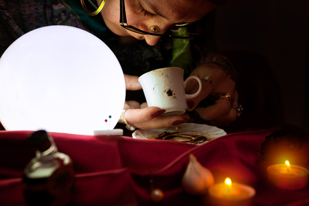 Fortune teller looking and read a fortune from empty coffee mug の写真素材