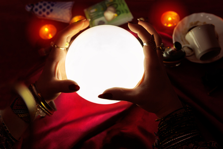 Hands of fortune teller with lighted crystal ball in the middleの写真素材