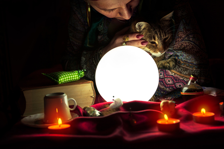 Woman fortuneteller with crystal ball and catの写真素材