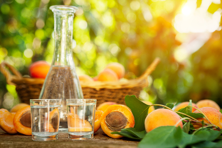 Fruit brandy in a glass and apricots on wooden tableの写真素材