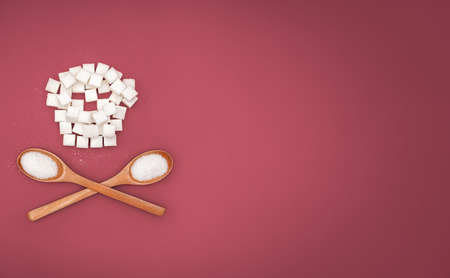 Skull of sugar and wooden spoons with sugar on red background