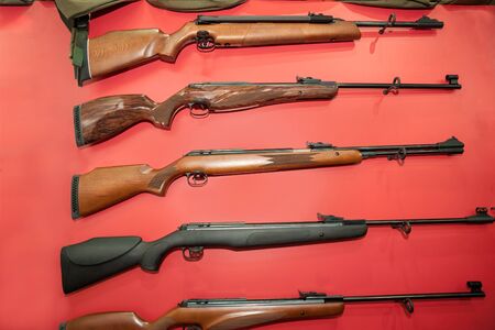 Different types of rifles hanging on the red wallの写真素材