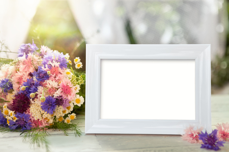 White frame and flowers bouquet on table.Empty white frame.の写真素材