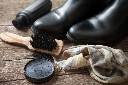 Polish cream black boots, brush and cloth on wooden tableの写真素材