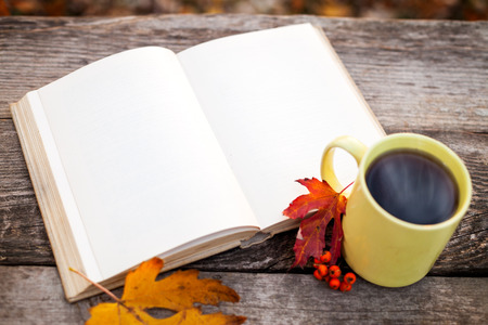 Book with open pages and cup with hot tea on wooden surfaceの写真素材