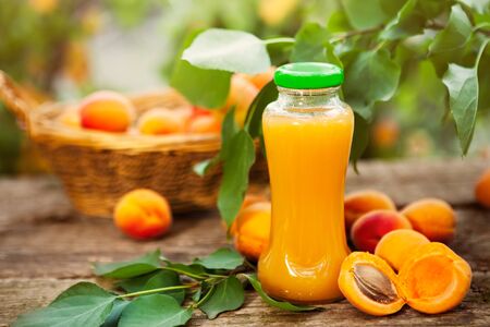 Bottle with apricot juice and delicious apricots on the tableの写真素材