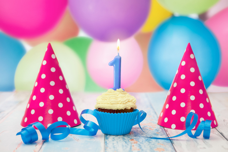 Cupcake decorated with candle with number,blue ribbon and party hatsの写真素材