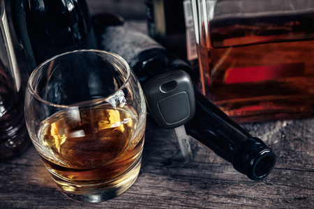 Car keys between glass of alcohol drink and empty bottleの写真素材