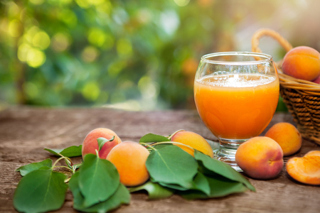 Tasty apricot juice in glass with apricots on the tableの写真素材