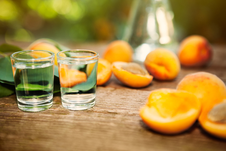 Shot glass with apricot alcohol brandy and fresh apricots on the tableの写真素材