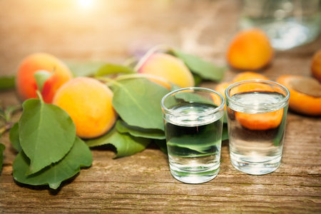 Shot glass with apricot brandy and apricot with leaf on the tableの写真素材