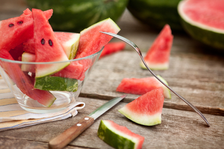 Watermelon pieces in glass bowl with fork and knifeの写真素材
