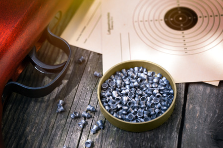 Pellets for rifle and paper target on wooden table