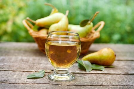 Glass with tasty pear juice with pears in the background