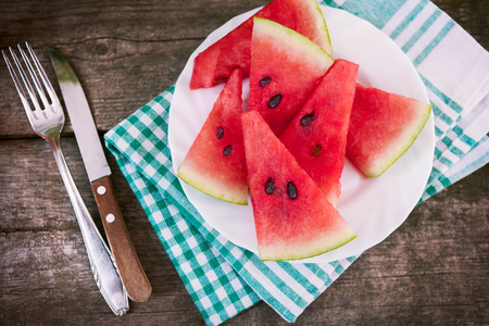 Watermelon cuts with plate on cloth and cutlery on the sideの写真素材