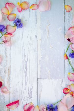 Wooden background with fallen petals and  flowers around itの写真素材
