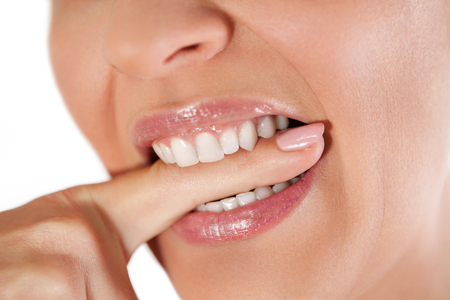 Woman biting finger with white teethの写真素材