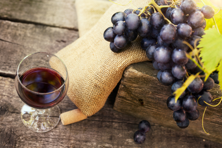 Glass of tasty red wine and grapes on wooden tableの写真素材