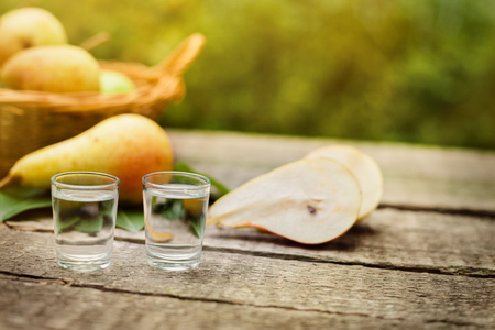 Pear brandy in shot glass and pears on the tableの写真素材