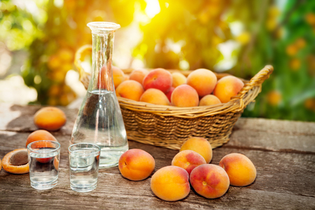 Fresh apricots with apricot brandy in shot glass and bottle on wooden tableの写真素材