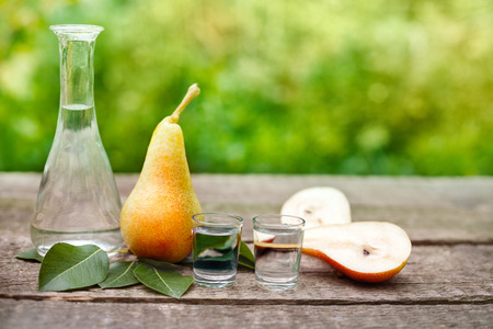 Fresh pears and shot glass with fruit brandy on the tableの写真素材