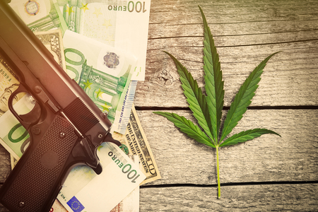 Marihuana with pistol and money bills on wooden tableの写真素材