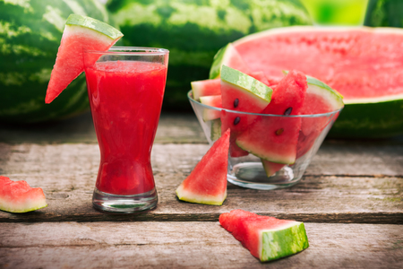 Cold watermelon cocktail in glass with watermelon in bowlの写真素材