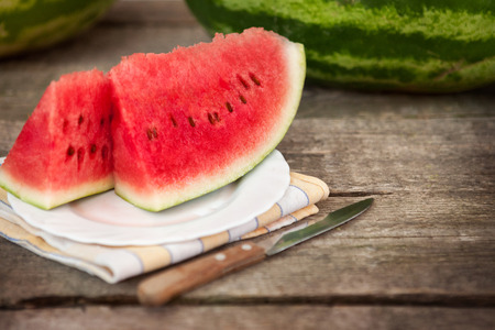 Sliced watermelon on plate and knife on wooden tableの写真素材