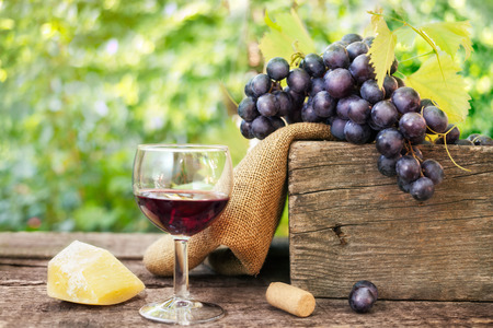 Cheese, grapes and glass of red wine on wooden surfaceの写真素材