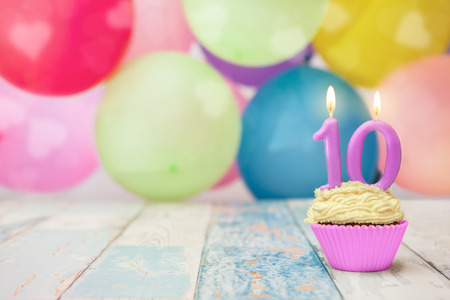 Birthday cupcake for tenth birthday with balloons in the backgroundの写真素材
