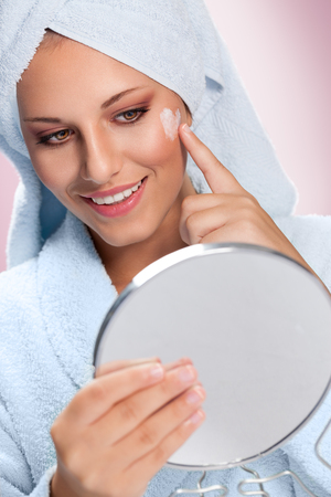 Happy woman taking care of her skin with moisturizing creamの写真素材