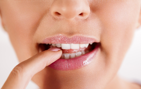Close up of provocative female lips biting finger with teeth の写真素材