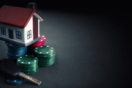 placing model house on pile of gambling chips, poker addiction.の写真素材