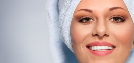 Beautiful young woman in white bathrobe with towel smilingの写真素材