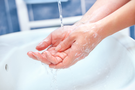 Hand washing under runnig water in bathrrom over the sinkの写真素材