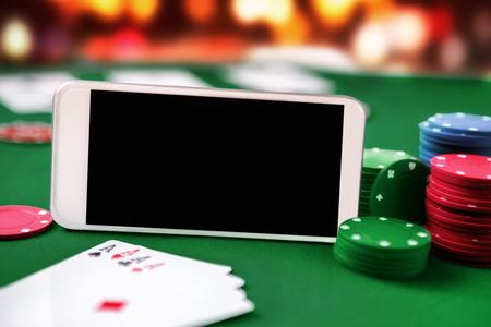 Smartphone with chip cards and four aces. Online poker gaming and gambling.の写真素材