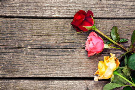 Top view of a beautiful bouquet of pink, red and yellow roses on old, rustic wooden background with the phrase Happy Women's Day 
の写真素材