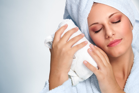 Beautiful woman in white bathrobe holding towelの写真素材