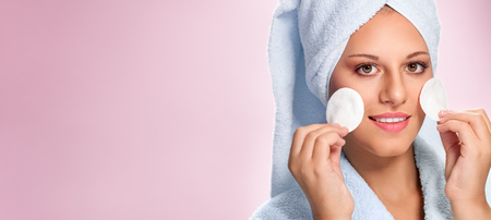 Young woman in bathrobe with clear skin holding cotton padsの写真素材